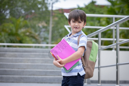 时尚随意的白种人带着背包微笑可爱的小男孩拿着书准备上学的第一天就绪图片