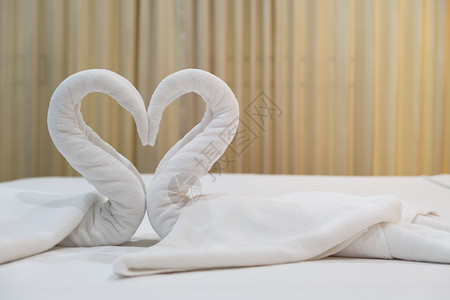 浪漫酒店床单上装有新鲜白浴巾的近身天鹅鸟客人房间背景图片