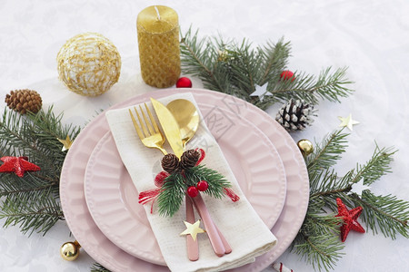 吃圣诞桌概念设置两个粉板和金餐具在纸巾锥形球和星上装饰昂贵的新图片