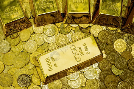 钱美丽的平坦在堆叠金硬币积一公斤的金条上图片