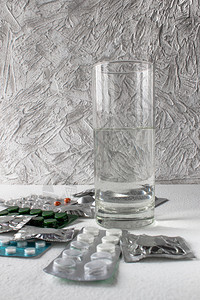 制药玻璃在一杯水丸附近用白色背景的包装粉末贴在一杯水药丸附近的一包白背景装粉末袋内封闭药片剂量图片