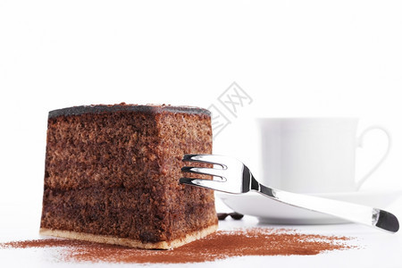 带叉子的巧克力蛋糕和背景中的一杯咖啡白色背景店可美食图片