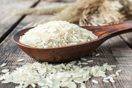 泰国有机的白米和木勺子在丝质茉莉花大米上用木勺子做近身白米饭用一根木勺子烹饪束图片