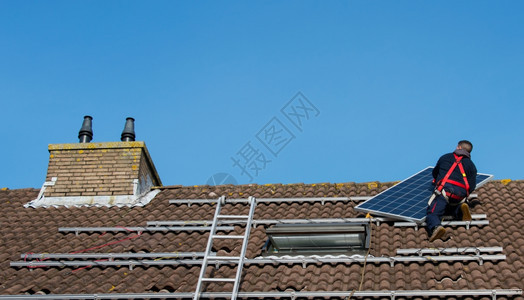把太阳能电池板放在屋顶上的男人图片