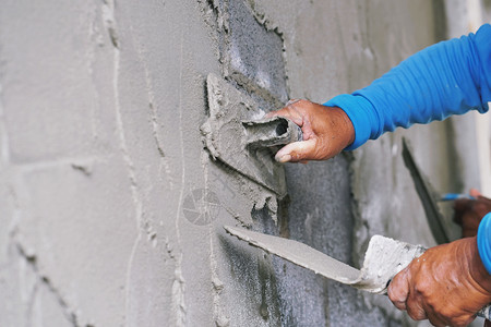 建造筑学墙上石膏水泥工人的手砖图片