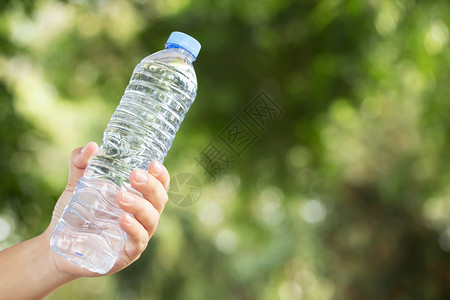 青年手握着公园塑料的淡水瓶在公园里举起手来活动跑图片