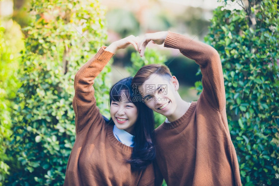 肖像女朋友热情美丽的年轻夫妇用手创造心形在户外的爱中快乐地微笑图片