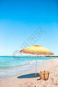 太阳毛巾在光明媚的一天在热带海滩上草袋的沙雨伞海背景有石头图片