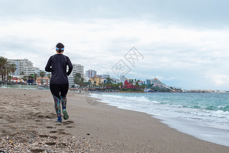 训练合身女人穿着黑衣服在海滩上奔跑夏天图片