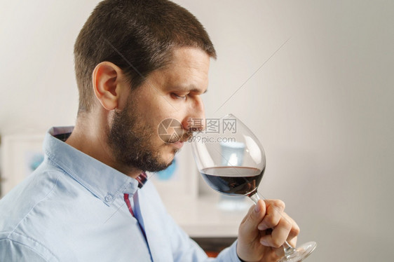 玻璃成年黑人男子穿着盛红酒杯的衬衫晚上或在家喝葡萄酒身着大胡子和短头发的男在家中紧闭满意白种人图片
