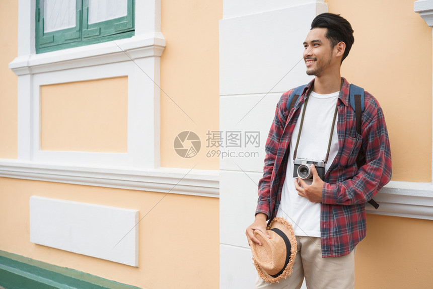 在泰国曼谷的吸引力索罗旅行和背包机概念中持有草帽的同时站在墙壁上观光的亚洲帅哥一种摄影师景点图片