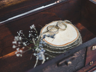 躺在鲜花背景上的两个结婚戒指特写图片