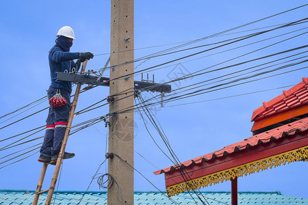 力量亚洲木制梯子技术员正在安装电缆线路将话和互联网信号系统连接到电线杆上使其与蓝天背景相连接风险攀登图片