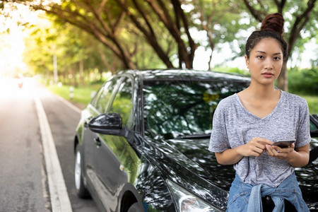 亚裔女在寻找时使用手机在街上因汽车故障而坐后女士人们休息图片