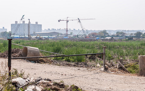 建造大型共有公寓的建筑工地入口处前面的金属路障该工地是建造大型公用寓的起重机白色挖掘图片