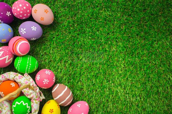 颜色快乐的质地在复活节和人造绿草上色的青复活节鸡蛋涂画花彩色多的青树上图片