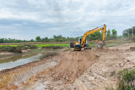 工人矿黄色挖掘机在施工现场进行土方程红色的图片