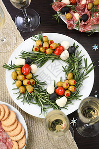 派对晚餐以圣诞花圈形式制作的盛开胃迷迭香配满橄榄和小奶油辣椒樱桃番茄新的图片