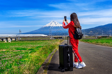 女士白色的观光客在日本藤山和高速火车上拍照图片