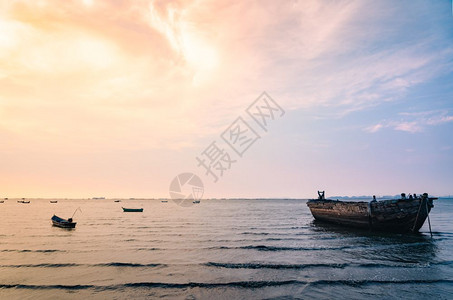 海滩红色的旅行美丽日落天空和海上的捕鱼船图片