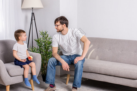 讲话男生父亲和年幼的儿子在家里客厅讨论一些严肃的事情信任家庭关系心理学父亲和年幼的儿子在家里客厅讨论一些严肃的事情对话图片