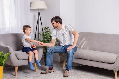父亲和年幼的儿子在家里客厅讨论一些严肃的事情信任家庭关系心理学父亲和年幼的儿子在家里客厅讨论一些严肃的事情偏僻压力活图片