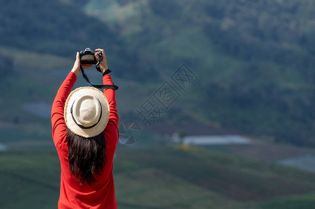 身着明亮红衬衫的亚裔女游客拍摄美丽的自然风景照像女旅游者拍摄自然照片背包明亮的夏天图片