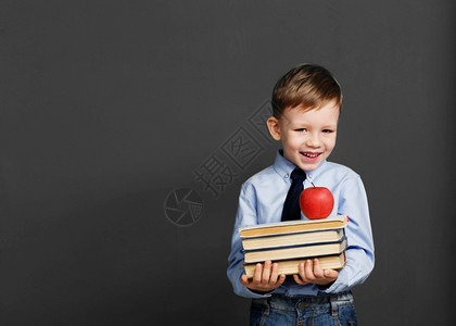 年轻的孩子书本学校小孩生拿着书笑的小孩反对黑板看着照相机又回到学校的概念保持图片