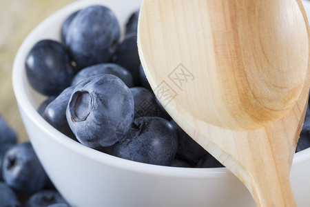 桌边的蓝莓在一碗白里夏天一张成熟和美味的浆果合照桌子上有一个生锈的木勺子瘦身营养生的图片