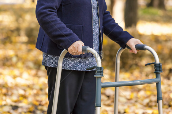 医疗的支持闲暇在秋季公园与步行者一起走的高级女子双腿闭合图片