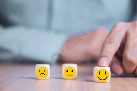 顾客手情绪商人选择一个微笑的表情图标在木块服务与客户满意度调查概念上面对快乐的象征图片