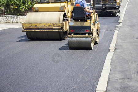 机器铺沥青工程道路建设期间的压滚机械工人图片