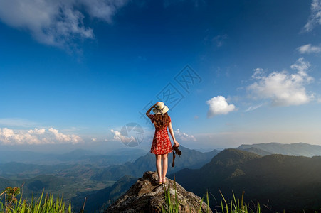 妇女手持照相机站在自然中的岩石顶上旅行概念美丽的站立闲暇图片