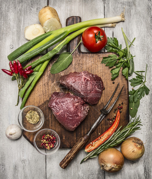烹饪牛肉排和秋天蔬菜的成分以及明亮生锈的木本底背景最佳视野在木制切割板上调味料配沙锅网站图片
