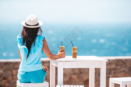鸡尾酒假期在户外咖啡厅的年轻女子喝冷咖啡享受海景的年轻女子微笑图片