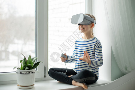 风镜男生一个戴着虚拟现实耳机的孩子坐在家里桌旁一个女孩通过视频和游戏探索虚拟现实世界未来的技术一个戴着虚拟现实耳机的孩子坐在家里图片