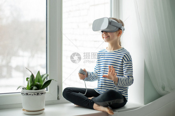 风镜男生一个戴着虚拟现实耳机的孩子坐在家里桌旁一个女孩通过视频和游戏探索虚拟现实世界未来的技术一个戴着虚拟现实耳机的孩子坐在家里图片