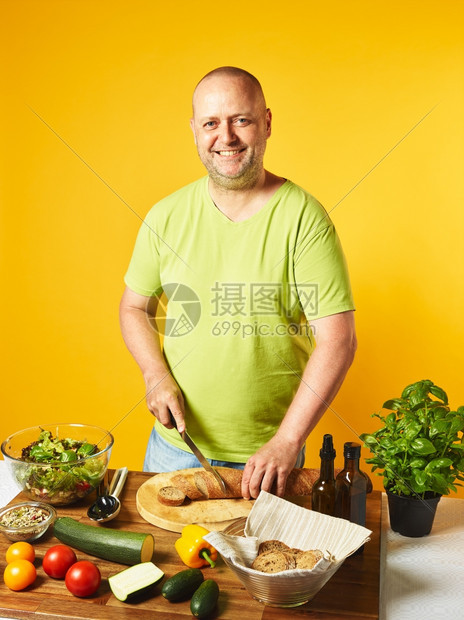 男餐桌上新鲜沙拉食品中年人切袋式面包圈复制空间和黄色背景红的成熟图片
