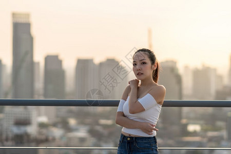 广告感的身穿时装衣的亚洲勇女人肖像站在城景背的屋顶上美丽体形概念的身材女士图片