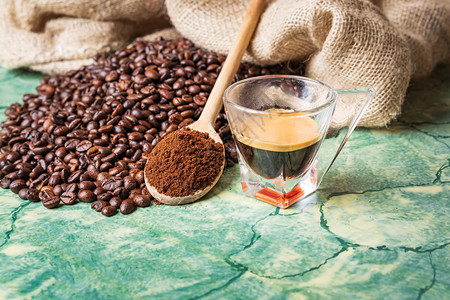 咖啡豆在绿桌上用泡布袋装咖啡的豆木制勺子上面加地咖啡和杯香气帆布浓咖啡图片