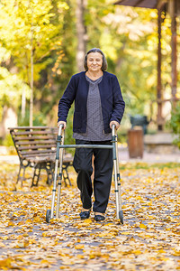 老的高级女子在秋季公园与步行者一起走在户外对着镜头微笑斗争花园图片