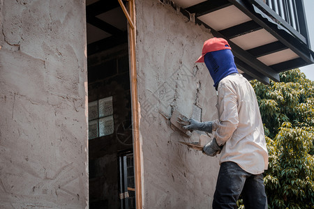 建筑工人使用水泥石膏在建筑墙上打石膏男人镘制服图片