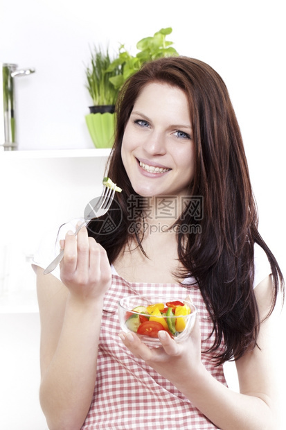 女营养在厨房吃混合沙拉的年轻快乐女青享受混合沙拉红色的图片