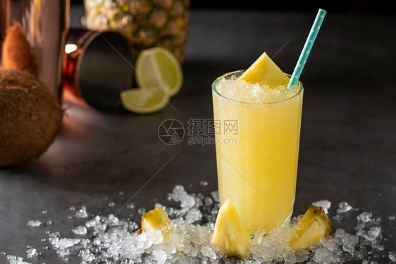 石背景中带菠萝椰子和柠檬的鸡尾酒黄色稻草热带图片