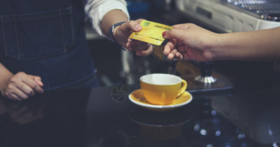柜台读者在咖啡店用信卡付咖啡费的是酒吧服务顾客和女招待在室内图片