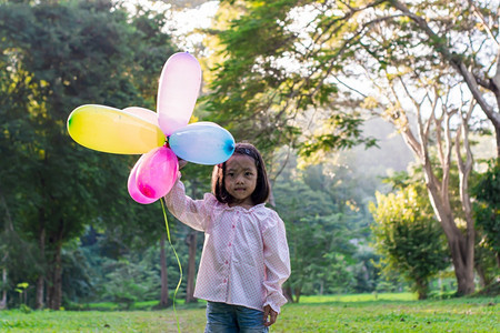 花园自由在公户外露天持有多彩玩具气球的女童肖像明亮图片
