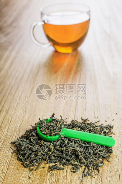 草本热的黄色在旧木桌上用勺子泡绿叶茶和汤匙图片