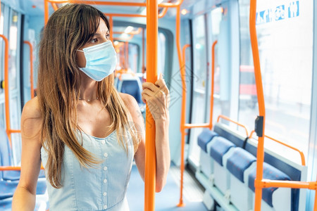 Covid19疫情爆发期间佩戴口罩的妇女乘坐电车旅行图片