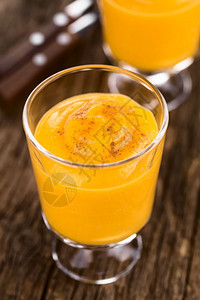 橙鲜自制南瓜甜点的三分之一是新鲜自制南瓜慕斯或涂满肉桂的杯子奶油在生锈木材选择焦点上拍摄乡村图片