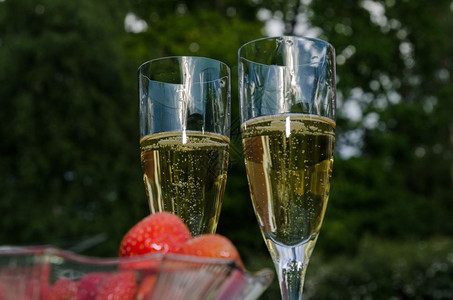 爱两杯外边有香槟的酒杯和一碗模糊的前台布满草莓景鸡尾酒图片